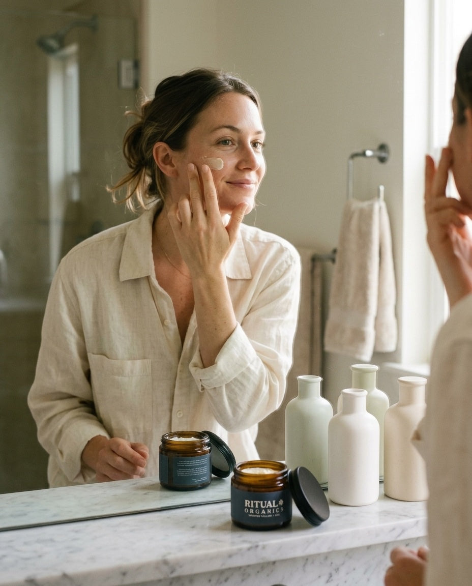 A woman applying whipped tallow balm at her bathroom mirror on an ordinary morning